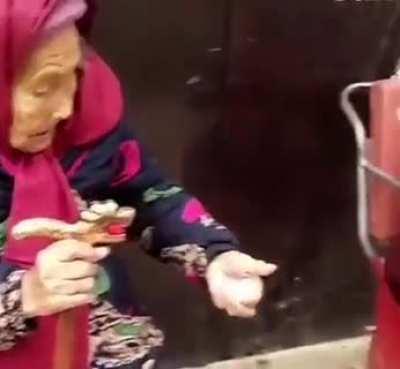 84-year-old daughter smiles after 107-year-old mother hands a sweet to her.