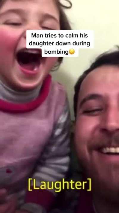 Super dad calming his daughter and making her laugh while the country is getting bombed.