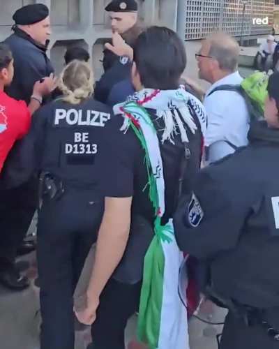 German police chasing a kid holding a Palestinian flag