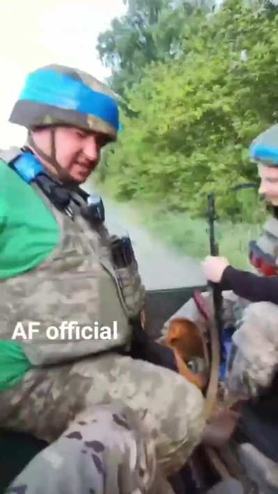 Ukrainian soldiers ride in the back of a pickup truck with an anti-drone jammer fitted.