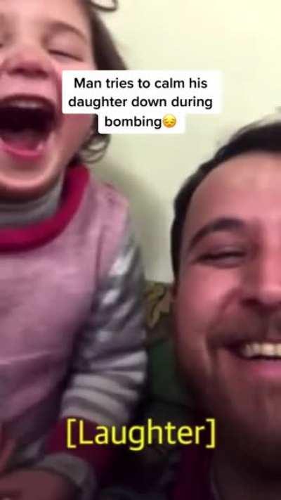 Super dad calming his daughter and making her laugh while the country is getting bombed.