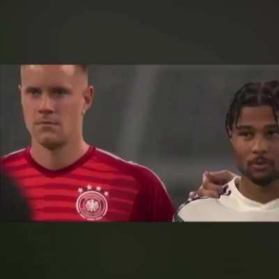 Someone sings national anthem during moment of silence for the terror victims of Halle at the GER:ARG match. Someone yells: 'Halt die Fresse!' (shut up). Audience applaudes, Gnabry smirks.