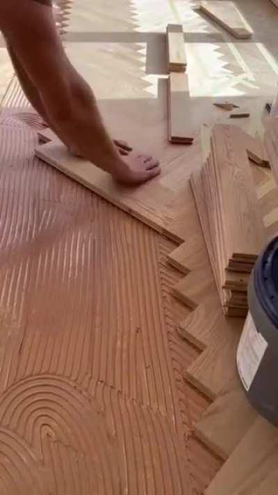 Installing a hardwood floor. This pattern is called Herringbone Parquet.