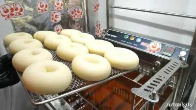 Extruding, frying, and glazing doughnuts at a small doughnut shop