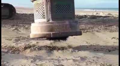 Pulling nails out of a beach bonfire site with a hydraulic scrap magnet.