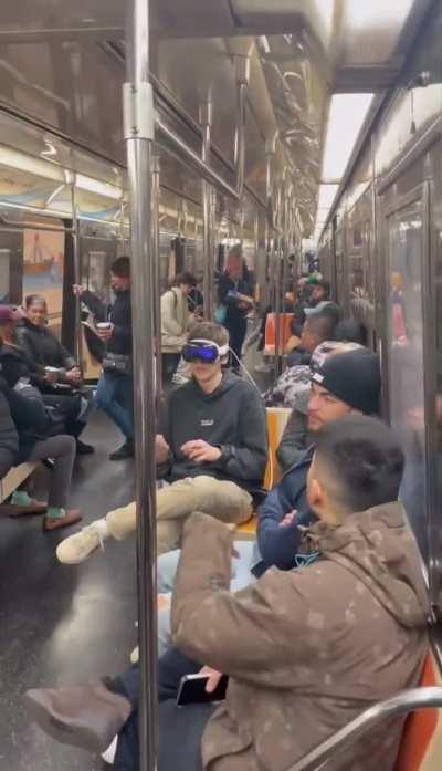 Guy using Apple Vision Pro on NYC subway.