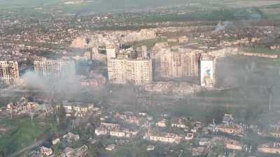 Daytime drone survey footage of destroyed Bakhmut (May 19, 2023) captures explosion of incoming shell next to renowned father/son high-rise mural at western entrance of city [source w/ add'l footage in comments]