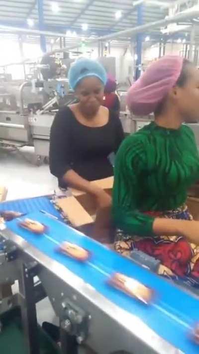 Workers at a biscuit company shows their mastery of filling a carton of biscuit