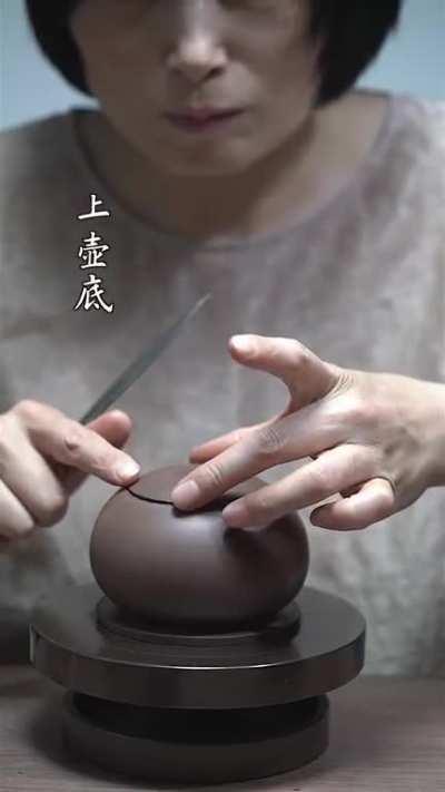 A lady making a teapot, she is so happy about it