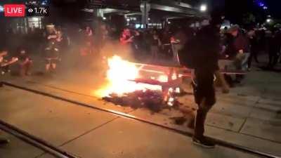 Popular antifa/BLM transvestite protestor, bailed out of jail recently for rioting, rides a burning picnic table in the street during tonight's riot