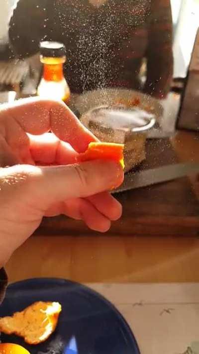 Squeezing orange peel in the sunlight