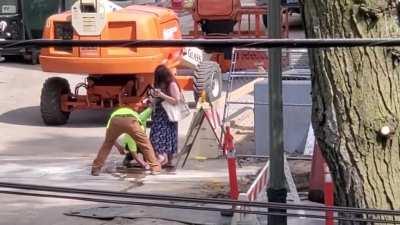 Construction workers washing off a blind woman's shoes after she walk through there site.