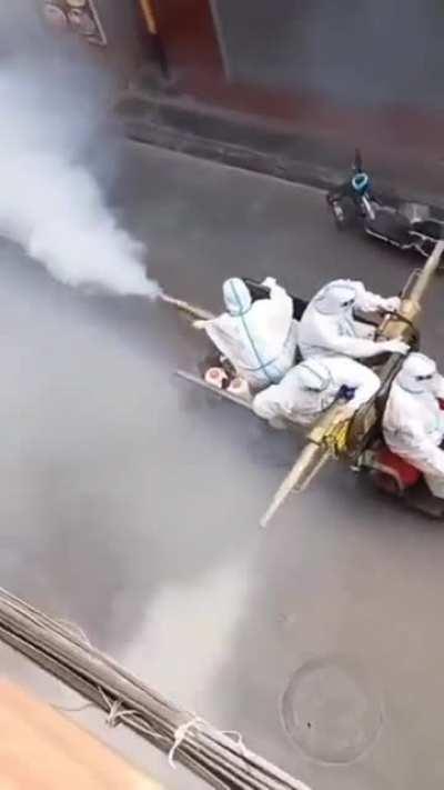 Chinese health workers spray down a street with ‘disinfectant’