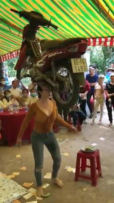 Vietnamese Woman can balance a moped on her head while dancing