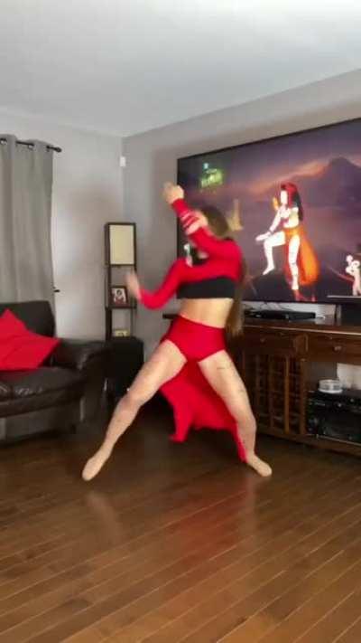 A girl in a red outfit dances enthusiastically in front of a television with a video of a similar girl. That is all.