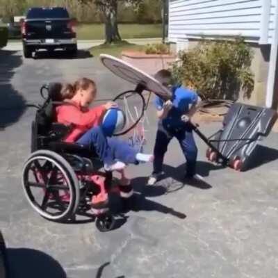 Brother helps his sister make the shot.