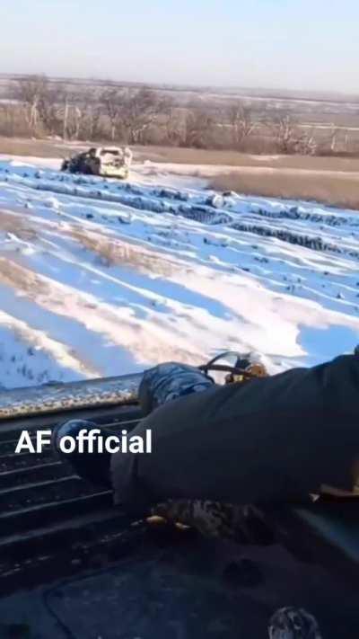 Ukrainian soldiers ride their BMP through the snow past the debris of earlier fighting.