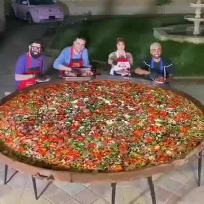 Man laughing while making giant pizza