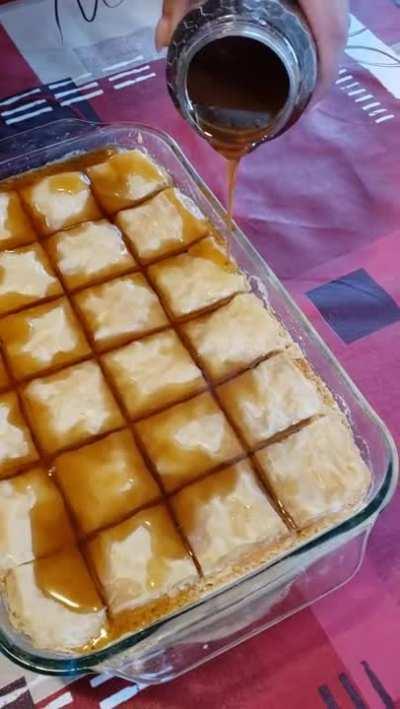 Putting the first layer of hot honey on a crispy Baklava.