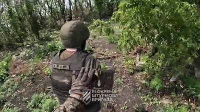 Wounded Russian soldier holds grenade while being captured.