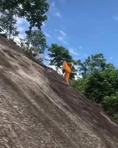 Monk climbs a steep hill with no ropes