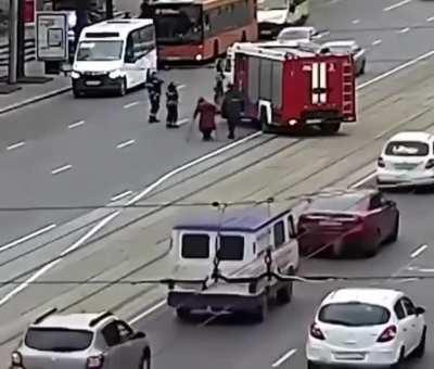 Firefighters help an elderly lady to cross the road