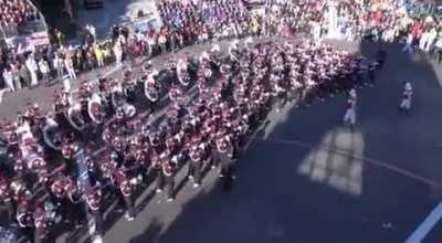 A marching band expertly maneuvering around a street corner during a parade