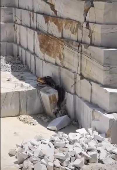 Excavator in a marble quarry looks like a toy