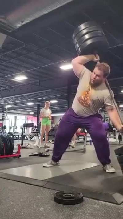 Man lifts 405 pound weight from the side, flips it onto his back, and does squats with it