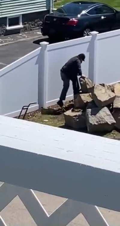 Man does his best trying to move a big rock.