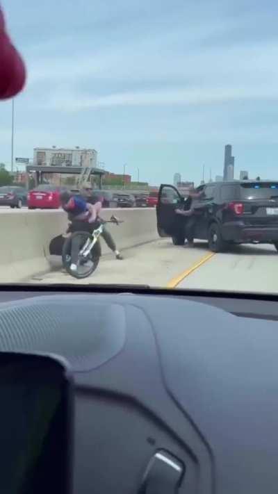 Main character riding a bicycle down a busy Chicago expressway