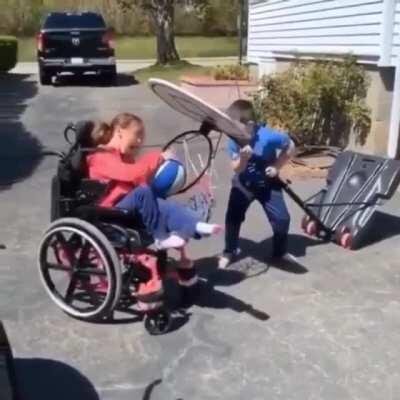 Brother helps his sister to make the shot.