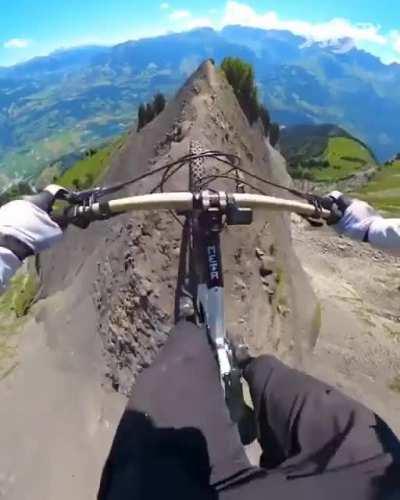 Riding a MTB on a narrow track on top of a hill