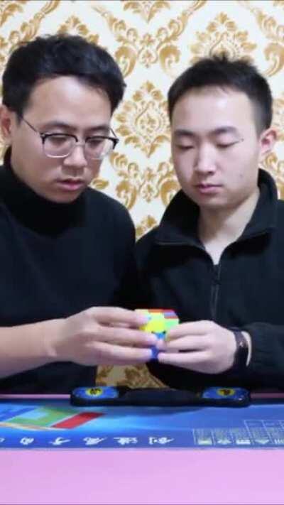 Two men (Xia Yan and Wang Penhcheng) speedcubing the same rubik's cube and break the world record (13.70 seconds)