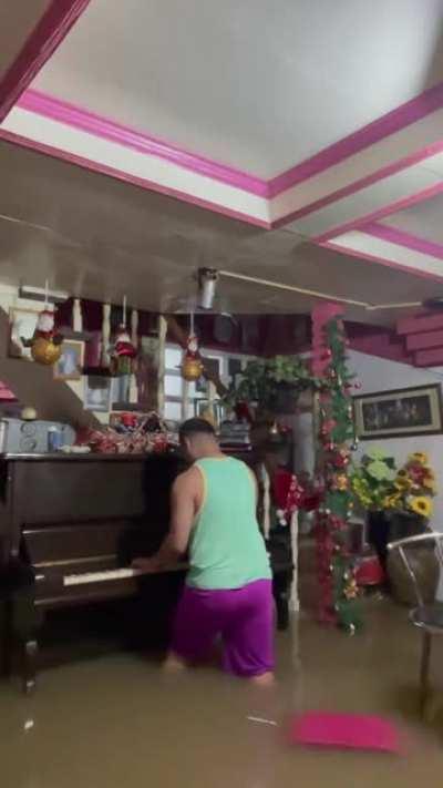 A man plays his 2 decade old piano for the last time before a flood that is brought by a typhoon destroys it.