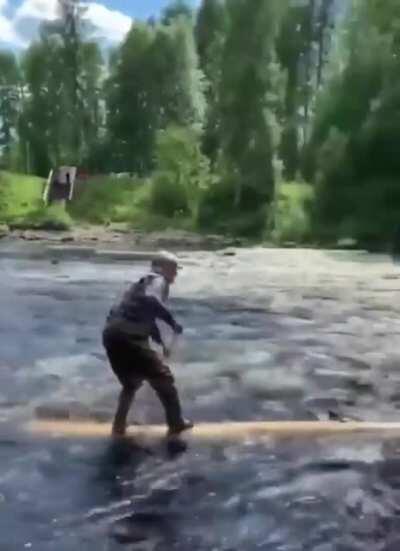 Grandpa riding and paddling on a log downstream and making it look easy