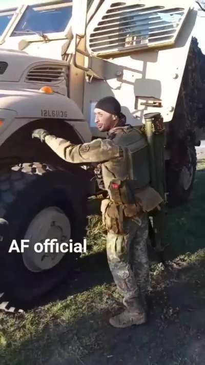 UKrainian soldier carrying an AT launcher enthusiastically shows off his MRAP.