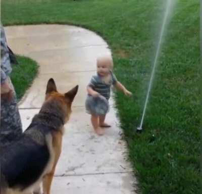 Toddler shows his buddy that a sprinkler is nothing to be afraid of