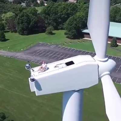 Drone captures a man sunbathing on a wind turbine