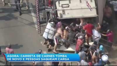 Carreta de carnes tomba e pessoas tentam saquear