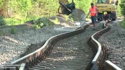 Straightening railroad tracks with a backhoe