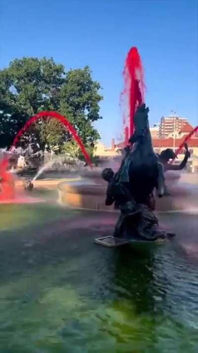 Pouring red dye into a public fountain