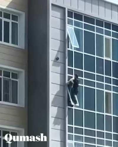 A guy saves little girl hanging from a window