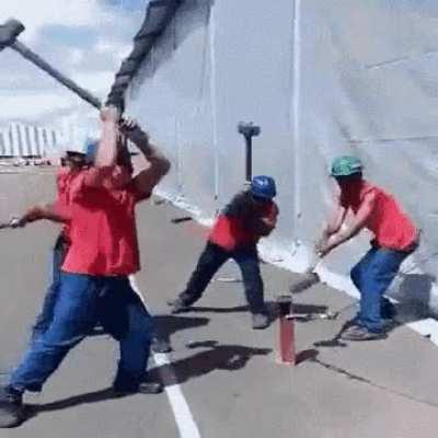 Multiple guys Hammering a Pole into the ground