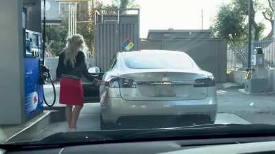 Woman trying to fill a tesla with gas