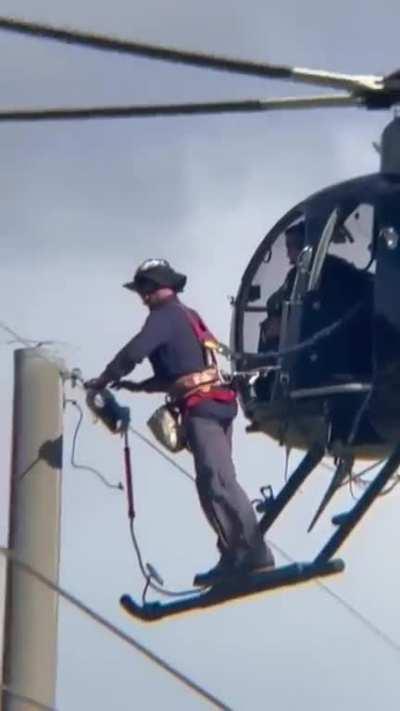 FPL worker in Florida fixing electric lines from an helicopter.