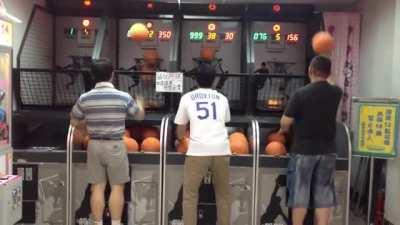 Asian dad locked in on a basketball arcade game