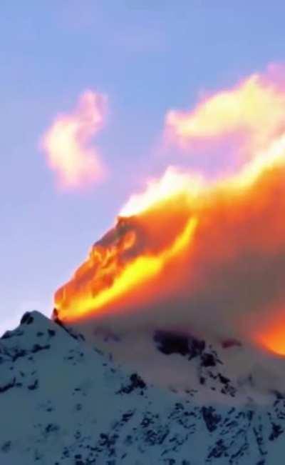 Sunset hitting the clouds on a mountaintop looks like wildfire.