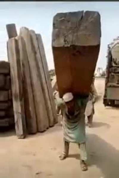 Man single Handedly carries massive wooden pillar