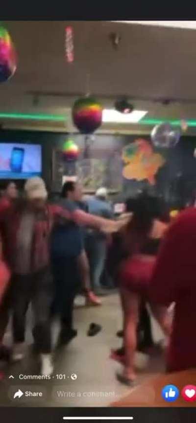 Lady dancing for camera, in front of giant bar fight